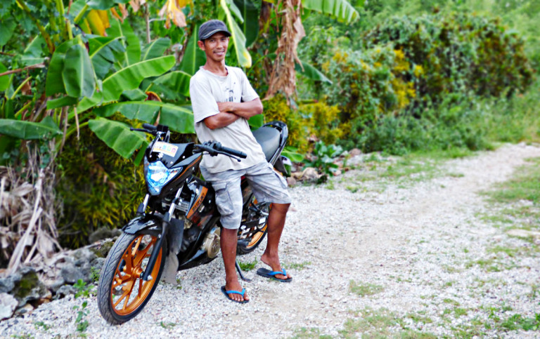 Elmar Tuma-on, an Isla Gigantes resident of Northern Iloilo, Philippines, poses with his new motorbike with his savings from tour guiding training provided through LGSP-LED.